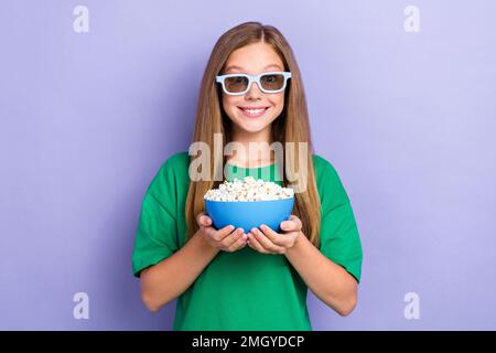 Foto des fröhlichen, hübschen Lady Hold Bucket köstlicher Snack Anschauen Sie faszinierenden Film Cartoon isoliert auf violettem Hintergrund Stockfoto