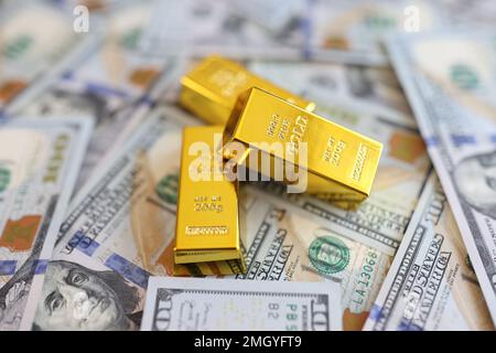 Goldbarren auf dem Hintergrund von US-Dollar-Banknoten Nahaufnahme. Stockfoto