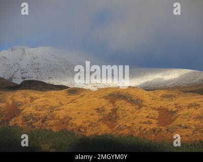 Schottlands Berge im Wintersonnenlicht: Blick nach Osten von Inverbeg über Loch Lomond in Richtung des schneebedeckten Ben Lomond. Stockfoto