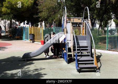 Vouliagmeni Athen Griechenland Thiseos Straße Spielplatz Familie spielt auf der Rutsche Stockfoto