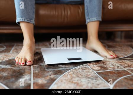 Damenbeine und Waagen auf dem Boden Nahaufnahme. Stockfoto