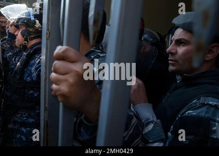 Beirut, Libanon. 26. Januar 2023. Mitglieder der inneren Sicherheitskräfte bleiben während einer Demonstration im Justizpalast in Beirut (Libanon) am 26. Januar 2023 in Sicherheit. Die Demonstration wurde von Familienmitgliedern von Opfern organisiert, die beim Beirut Blast getötet wurden. Die Demonstranten, wütend über Richter Ghassan Oueidat, die alle Gefangenen im Zusammenhang mit der Explosion gestern freigelassen haben, sind durch ein Tor eingedrungen. Ein paar Demonstranten wurden verletzt, aber sie schafften es, ein paar Sicherheitsleute auf die Straße zu ziehen und sie anzugreifen. Der Sicherheitsdienst reagierte, indem er Pfefferspray in die Menge spritzte. Anderswo im Libanon demonstrieren Menschen Stockfoto