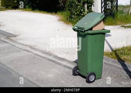 Rollender grüner Mülltonnen, der in Straßenstädten über dem Sack-Wheelie floss Stockfoto