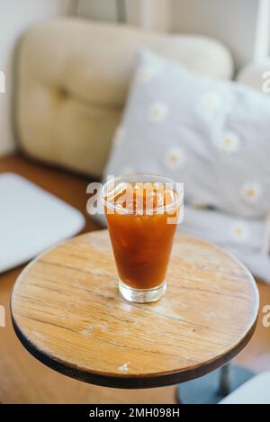 Eisgekühlter Americano-Kaffee auf einem hölzernen Café-Tisch im Innenbereich Stockfoto