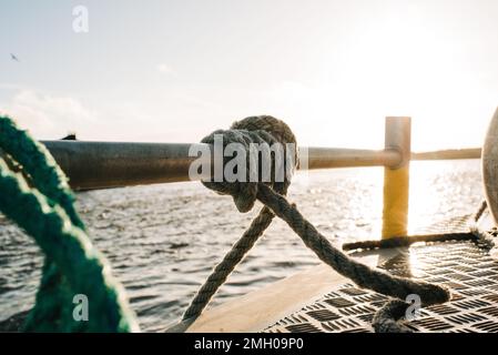 Ein Seil, das bei Sonnenuntergang auf einem Boot verknotet ist Stockfoto