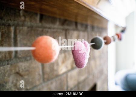 Nahaufnahme des farbenfrohen Filz-Valentinsgarlands am Kamin Mantle Stockfoto