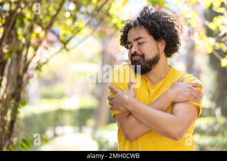 Junger Mexikaner mit Bart und Afro, der sich umarmt, Selbstliebe Stockfoto