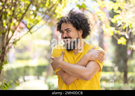 Junger Mexikaner mit Bart und Afro, der sich umarmt, Selbstliebe Stockfoto