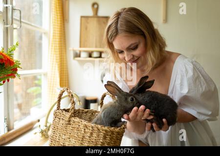 Eine Frau hält Kaninchen, lächelt, Osterkonzert Stockfoto