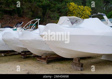 Motorbootparkplatz überdachte weiße schützende Plastikfolie Neue moderne Boote in Hülle Schrumpffolie auf Segelboot gelagert für die Saison kalten Winter Stockfoto