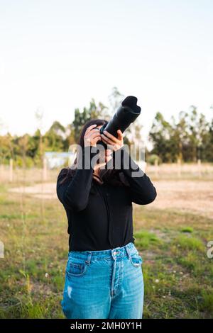 Junge, nicht erkennbare Amateurfotografin, die mit einem Teleobjektiv in den Himmel fotografiert. Stockfoto