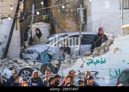 Dschenin, Naher Osten. 26. Januar 2023. Die Palästinenser inspizieren die Überreste zerstörter Anlagen und Fahrzeuge, die während des Sturms der Stadt Dschenin im besetzten Westjordanland durch einen israelischen Bulldozer beschädigt wurden. Große Streitkräfte der israelischen Armee stürmten die Stadt Dschenin und töteten zehn Palästinenser, darunter eine Frau, und verwundeten während der Zusammenstöße zwischen ihnen und den Kräften, mit denen sie konfrontiert waren, mehr als zwanzig weitere mit lebenden Kugeln. Die Armee sagte, dass die Razzia auf einer Wohnung der Zelle im Flüchtlingslager Dschenin stattfand, die nach "genauen Informationen" begann, die von t bereitgestellt wurden Stockfoto