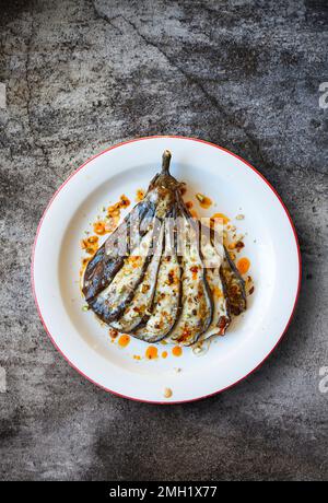 Gebackene Aubergine, gekleidet mit Harissa und Pistazien. Stockfoto