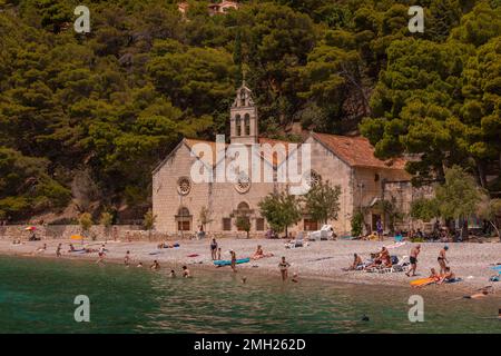 KOMIZA, KROATIEN, EUROPA - die Menschen genießen den Strand in der Küstenstadt Komiza, auf der Insel Vis, in der Adria. Stockfoto