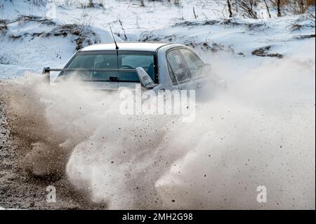 Tukums, Lettland - Januar. 7. 2023: Kinder üben mit dem Straßensportwagen Mitsubishi Lancer Evo sicheres Fahren auf der Winterstrecke Stockfoto