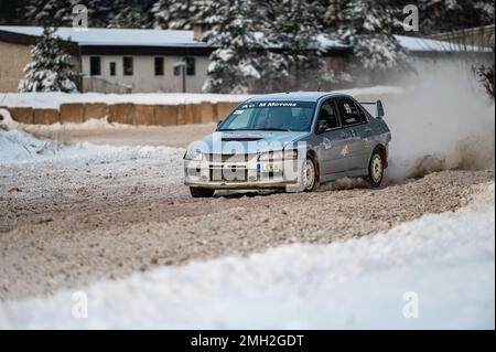 Tukums, Lettland - Januar. 7. 2023: Kinder üben mit dem Straßensportwagen Mitsubishi Lancer Evo sicheres Fahren auf der Winterstrecke Stockfoto