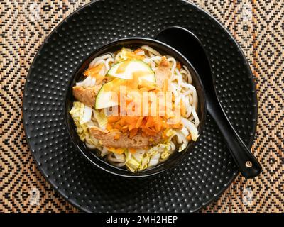 Asiatische Suppe mit Mie-Nudeln, TVP, Kohl, Zucchini und gehackten Karotten. Stockfoto