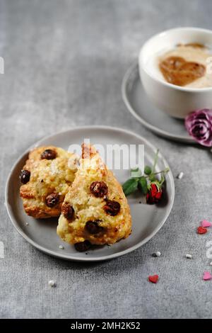 Frühstücksraum am Valentinstag - Scones Cappuccino Herz und Rosen auf einem Tablett, selektiver Fokus Stockfoto
