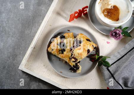 Frühstücksraum am Valentinstag - Scones Cappuccino Herz und Rosen auf einem Tablett, selektiver Fokus Stockfoto