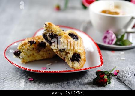 Frühstücksraum am Valentinstag - Scones Cappuccino Herz und Rosen auf einem Tablett, selektiver Fokus Stockfoto