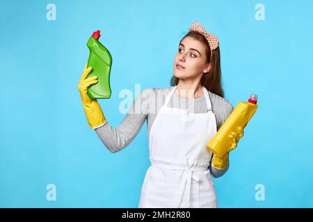 Frau mit Gummihandschuhen wählt zwischen zwei Reinigungsprodukten Stockfoto