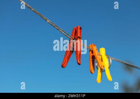 Bunte Wäscheklammern an den Kleiderbügeln. Kunststoffkleideräume in verschiedenen Farben. Stockfoto