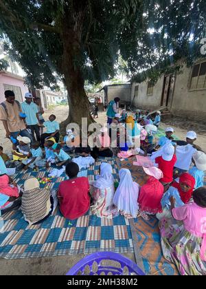 Arme Kinder sitzen zusammen mit Erwachsenen und genießen das Leben im Waisenhaus. Die armen Kinder sitzen im Kreis und spielen. Sansibar, Tansania, Stockfoto