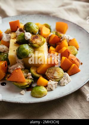 Salbei Polenta mit gerösteten Rosenkohl, Winterkürbis und hausgemachtem veganen Fetakäse Stockfoto