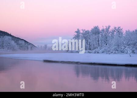 Die rosafarbenen Pastelltöne von Sunrise verleihen der kalten Winterlandschaft am Ufer des Knik River im südlichen Zentralaska Wärme. Stockfoto