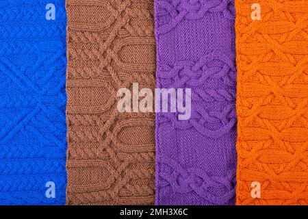 Gestrickter Hintergrund: Blau, lila, braun und orange. Großer Strickstoff mit Muster. Nahaufnahme einer Strickdecke. Stockfoto