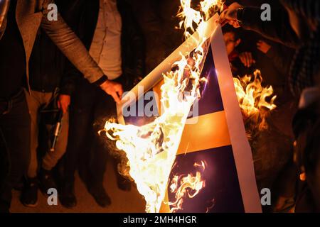 Idlib, Syrien. 26. Januar 2023. Syrische Demonstranten verbrennen ein Banner mit der schwedischen Flagge während eines Protests gegen das Verbrennen einer Kopie des Korans durch einen schwedischen Politiker. Muslime weltweit sind empört, nachdem der dänisch-schwedische Politiker Rasmus Paludan eine Demonstration vor der türkischen Botschaft in Stockholm organisiert hat, bei der er eine Kopie des heiligen Korans verbrannte. Kredit: Anas Alkharboutli/dpa/Alamy Live News Stockfoto