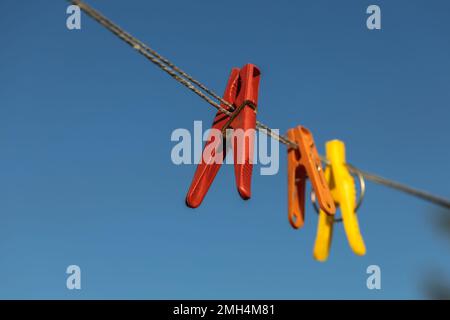 Bunte Wäscheklammern an den Kleiderbügeln. Kunststoffkleideräume in verschiedenen Farben. Stockfoto