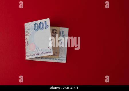 Eine Hand hält eine Banknote von 100 yuz turk lirasi auf rotem Hintergrund Stockfoto