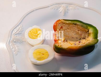 Eine halbe süße Paprika, eine Paprika, Capsicum annumm, gefüllt mit Pimento-Käse und serviert auf einem weißen Gericht mit einem gekochten Ei. Stockfoto