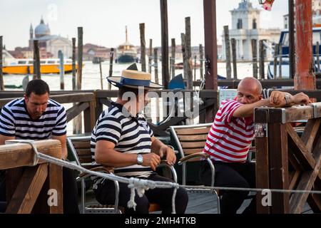 3 Gondoliers warten auf die nächsten Kunden, die in der Nähe der Lagune in Venedig sitzen Stockfoto