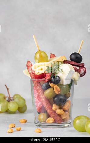 Jarcuterie in einem Glas umfasst verschiedene Arten von Würsten, Gurken, Käse, Nüssen, Gemüse und Obst. Moderne Version eines festlichen Snacks Stockfoto