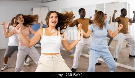 Fröhliche, energetische, multirassische Tänzer unterschiedlichen Alters, die Aerobic im Unterricht in der modernen Fitnessklasse tanzen Stockfoto