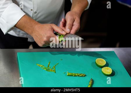 Der Koch, der Spargel hackt. Gemüse mit einem Messer hacken Stockfoto