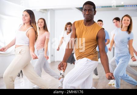 Aufregende, sportliche, multiethnische Menschen, die während des Tanztrainings im Studio neue Bewegungsschritte üben Stockfoto