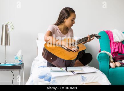 Eine Teenagerin, die Gitarre spielt. Stockfoto