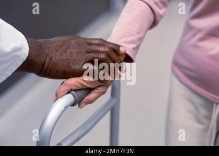 Nahaufnahme eines afroamerikanischen Arztes und eines erfahrenen Kaukasier-Patienten, der Händchen hält Stockfoto