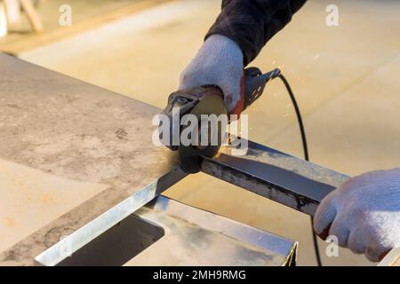 Das Metall wird von einem Arbeiter geschnitten, der während der Arbeit mit dem Schleifgerät arbeitet Stockfoto