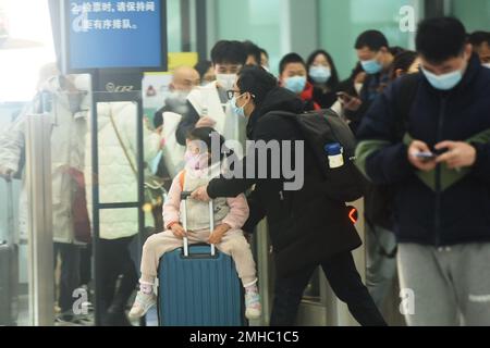 HANGZHOU, CHINA - 27. JANUAR 2023 - Junge Passagiere und ihre Eltern warten auf einen Hochgeschwindigkeitszug am Ostbahnhof Hangzhou in Hangzhou, Osten Stockfoto