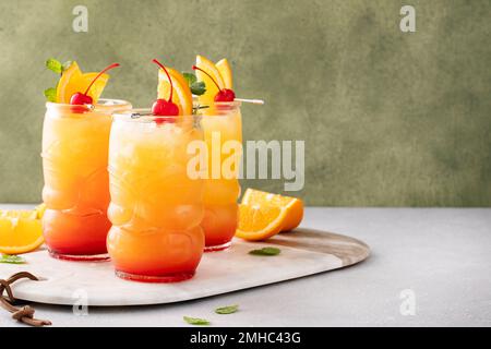 Rumpunsch in Tiki-Gläsern mit Orangenscheiben und einer Kirsche Stockfoto