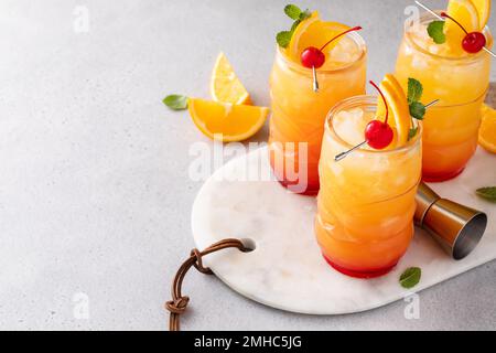 Rumpunsch in Tiki-Gläsern mit Orangenscheiben und einer Kirsche Stockfoto