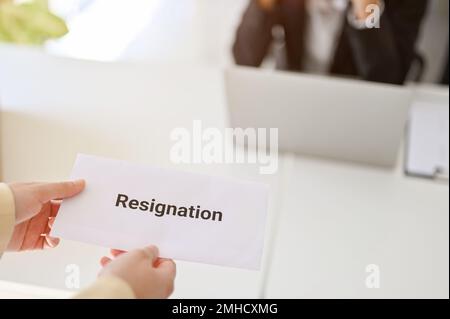 Eine Geschäftsfrau oder Büroangestellte, die ihren Rücktritt ihrem Chef im Büro übergibt. Nahaufnahme Stockfoto