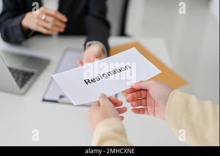 Eine Geschäftsfrau oder Büroangestellte, die ihren Rücktritt ihrem Chef im Büro übergibt. Den Job zu verlassen, einen Job zu wechseln, um eine bessere Position zu bekommen. clo Stockfoto