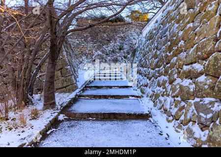 Schneebedeckte Treppen durch alte Steinmauern der Burg Stockfoto