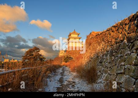 Schnee auf dem Weg an der Schneewand zum historischen japanischen Schloss im goldenen Morgenlicht Stockfoto