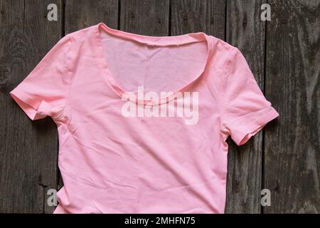 Pinkfarbenes Damen-T-Shirt flach liegend auf rustikalem braunem Hintergrund, Damenbekleidung, Mode Stockfoto